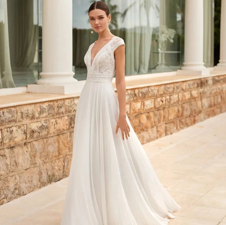 Robe de mariée bohème dos nu en dentelle avec décolleté plongeant, longue traîne, idéale pour un mariage romantique et élégant.