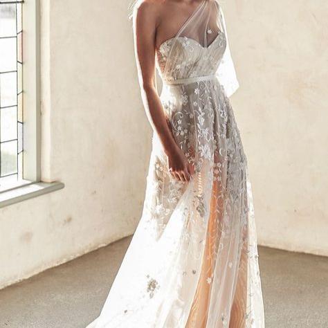 Robe de mariée bohème beige avec dentelle et détails floraux, portée par Anna Campbell Lumière, élégante et romantique.