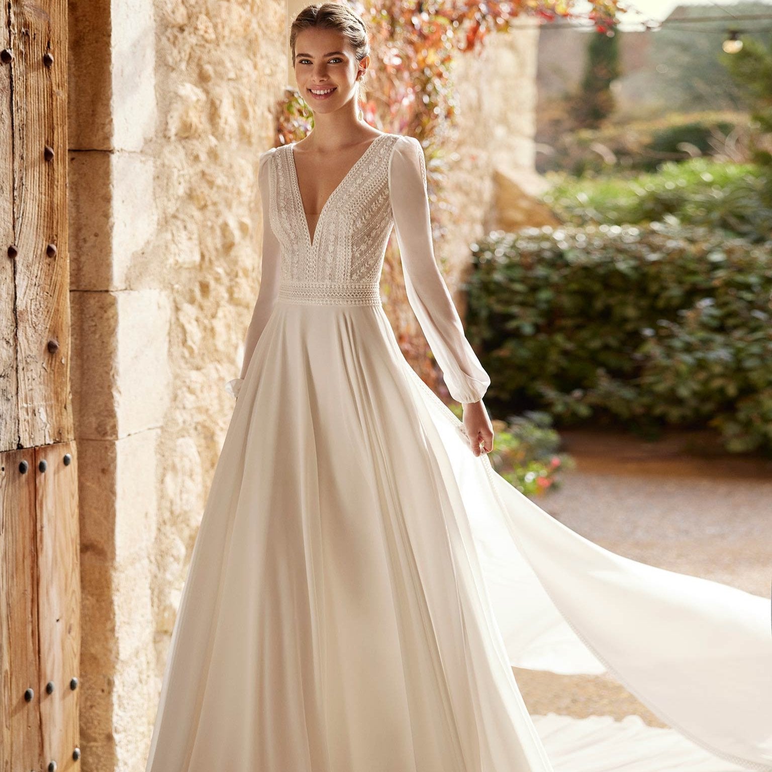 Robe de mariée bohème hiver avec dentelle et manches longues, portée par une modèle dans un décor romantique.