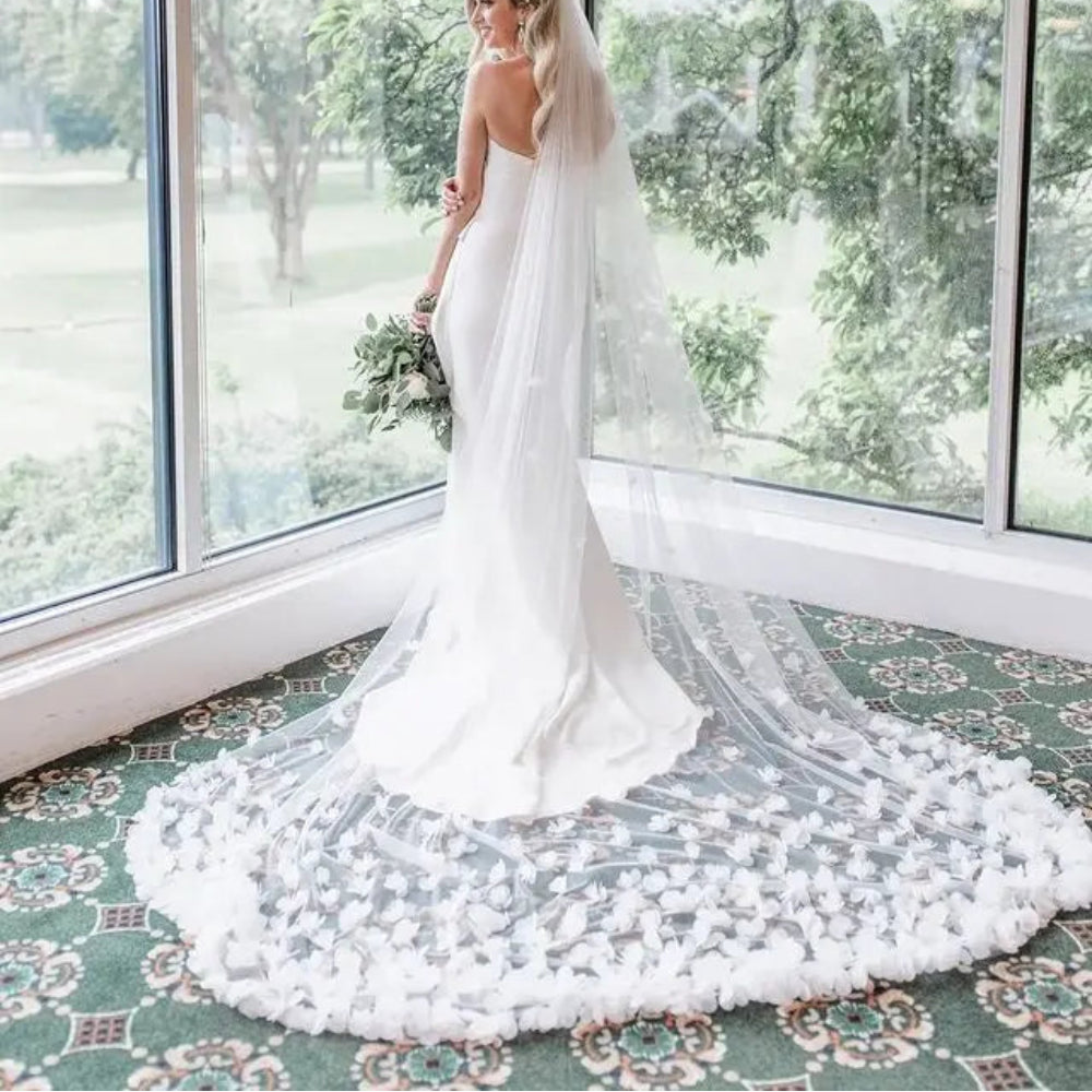 Voile long de mariée en tulle léger, style bohème, porté avec une robe de mariée élégante et fluide.