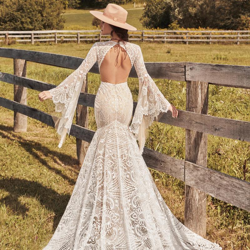 Robe de mariée bohème hippie avec dentelle délicate et jupe fluide, portée par une modèle dans un cadre romantique.