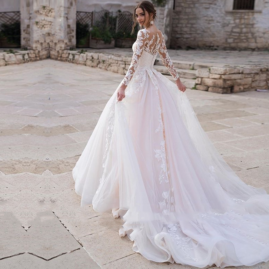 Robe de mariée bohème rose avec dentelle délicate et jupe fluide, idéale pour une mariée romantique et élégante.