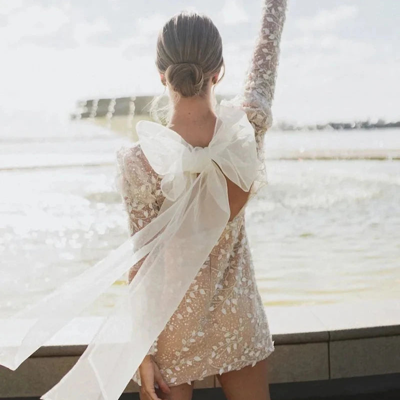 Robe de mariée bohème 2021 avec dentelle fluide, manches longues et détails délicats, portée par une mannequin dans un décor naturel
