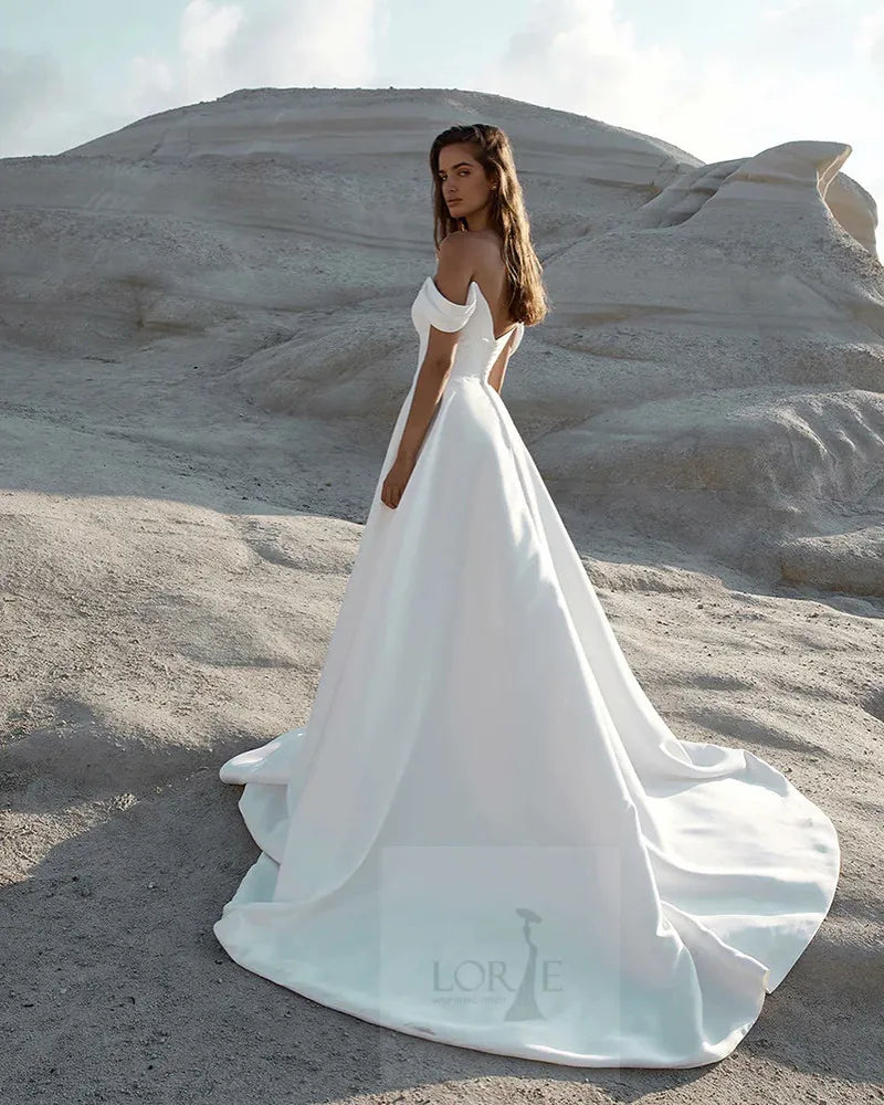Robe de mariée asymétrique de Robe de mariée Paris, longue en tissu fluide avec décolleté élégant et détail unique.