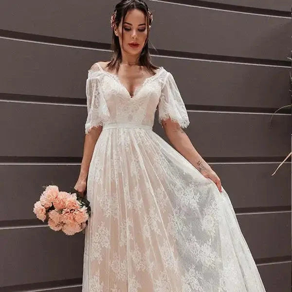 Robe de mariée bohème blanche avec dentelle, longue et fluide, portée par une mannequin dans un décor naturel.