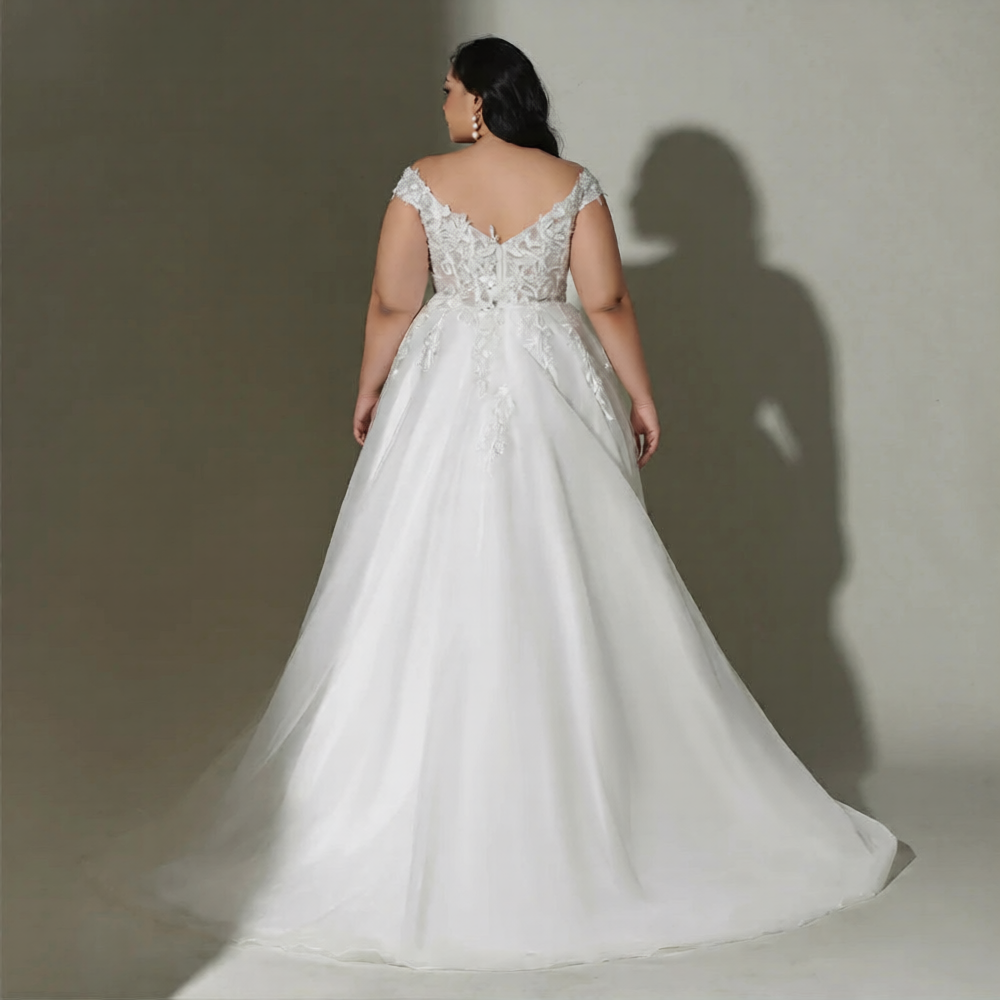 Robe de mariée courbe élégante de la marque Robe de Mariée Paris, en tissu blanc avec détails en dentelle et décolleté.