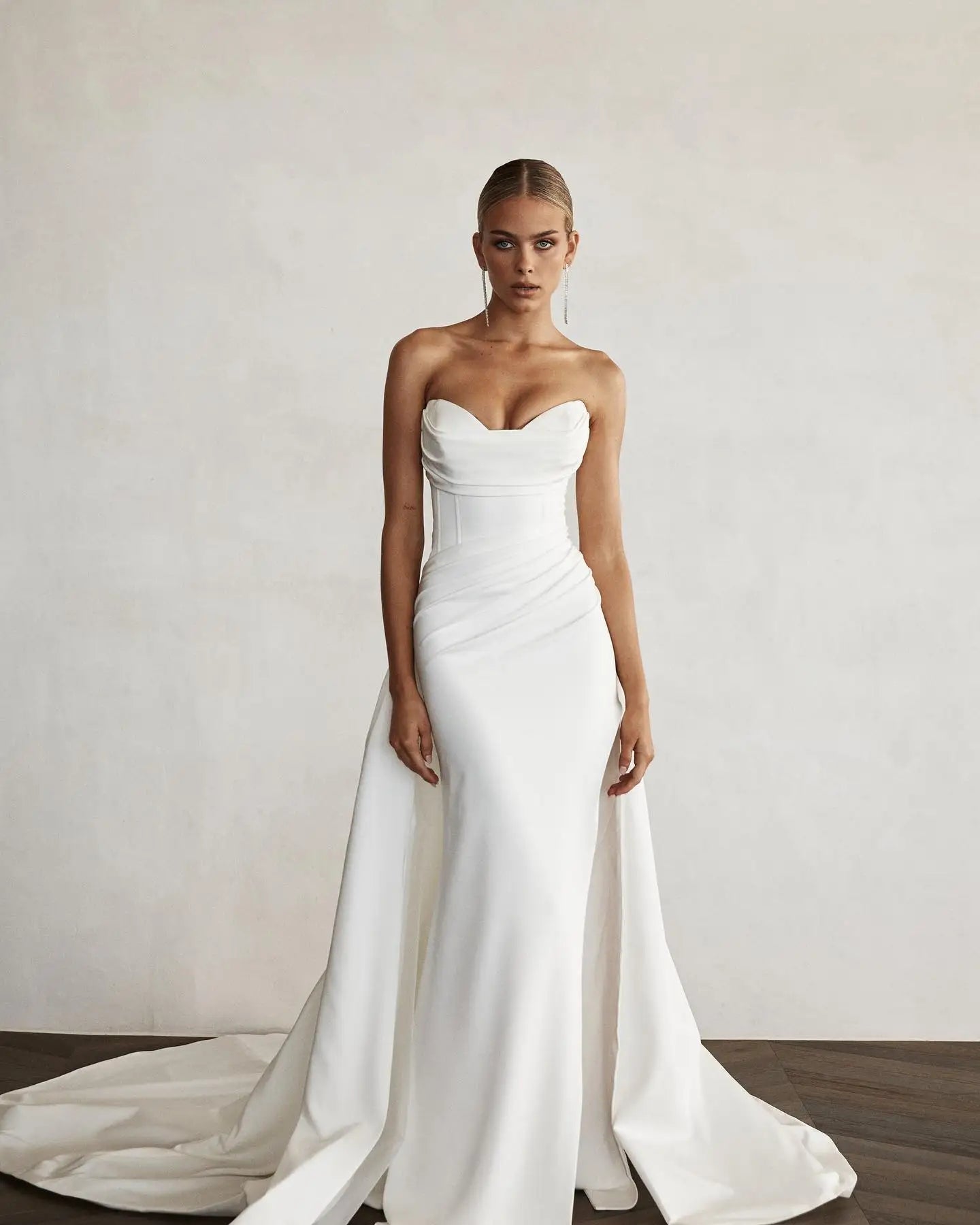 Robe de mariée sirène avec traîne de la marque Robe de mariée Paris, en satin blanc, détail de la jupe ajustée et traîne longue.